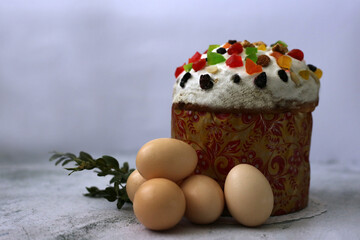 Easter cake decorated with candied fruits next to eggs on a gray background