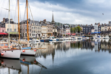 Honfleur, Normandy / France - August 27, 2020. World heritage in Calvados, Normandy, France. Panoramic view of the picturesque harbour of Honfleur, yachts and old houses reflected in water.