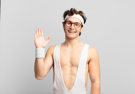 humorous sport man smiling happily and cheerfully, waving hand, welcoming and greeting you, or saying goodbye