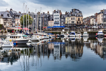 Fototapeta na wymiar Honfleur, Normandy / France - August 27, 2020. World heritage in Calvados, Normandy, France. Panoramic view of the picturesque harbour of Honfleur, yachts and old houses reflected in water.