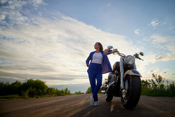 Fototapeta premium Attractive brunette motorcyclist with motorcycle in a summer evening during sunset. Adventure and travel concept.