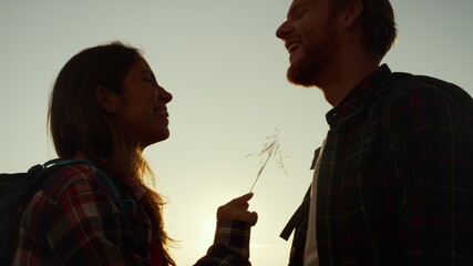 Laughing couple with backpacks looking at each other at sunset in mountains