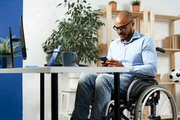 Mixed raced disabled man sitting in a wheelchair and using smartphone