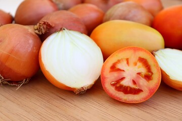 Tomatoes and onions on wooden background.