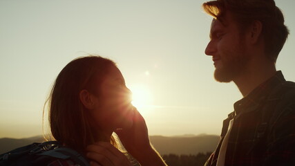 Affectionate man looking in woman eyes. Couple standing on top of mountain