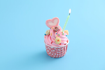 Colorful cupcake with candle isolated in blue background