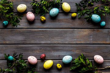 Frame of Easter eggs with spring branches and green leaves. Veiw from above