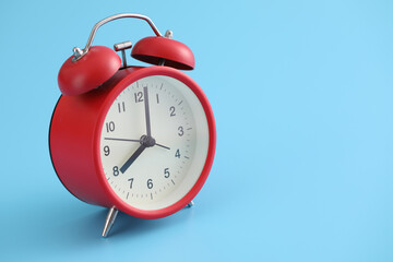 Red retro alarm clock isolated on a blue background