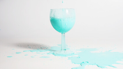 Glass with spilled mint liquid on a white background