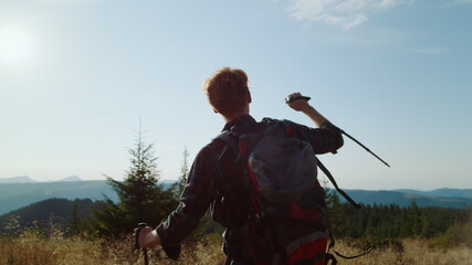 Man raising hands in air during hike in mountains. Happy hiker feeling freedom