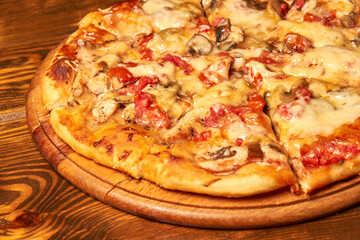 Pizza with cheese, tomatoes and mushrooms on a wooden board. Close-up, selective focus.