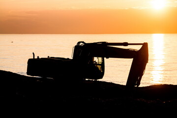 Industrial machinery working at beach in sunset