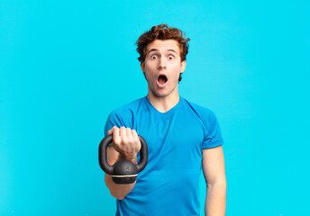 young sport boy looking very shocked or surprised, staring with open mouth saying wow. dumbbell...