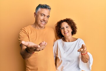 Beautiful middle age couple together wearing casual clothes smiling cheerful offering palm hand giving assistance and acceptance.