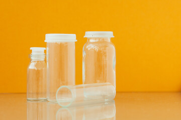 Transparent phials on yellow background. Small empty bottles