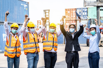 Group of employees and management team wearing logistic uniforms for exporting products abroad, stand to celebrating or raise their hands together to manage at the container yard