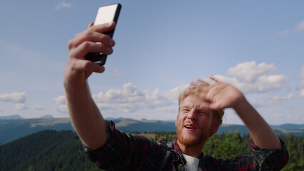 Man talking by video call online on smartphone. Hiker waving hand at camera