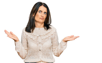 Middle age brunette woman wearing casual clothes clueless and confused expression with arms and...
