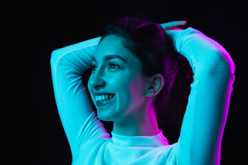 Portrait of young beautiful girl isolated on dark background in neon light