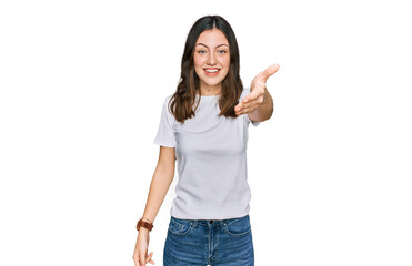 Obraz premium Young beautiful woman wearing casual white t shirt smiling friendly offering handshake as greeting and welcoming. successful business.