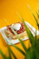 Delicious breakfast. Scrambled eggs with bacon on a yellow background