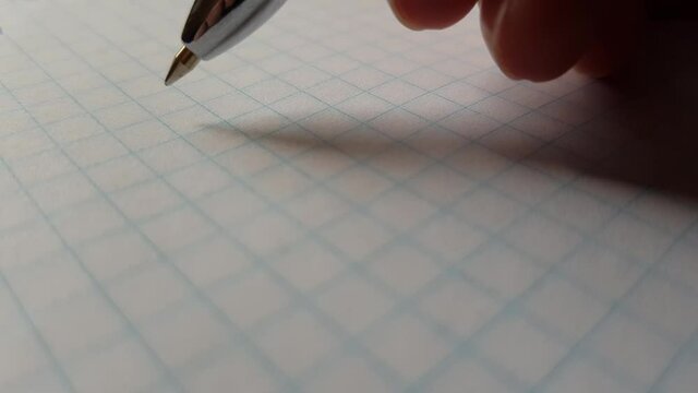 A hand with a blue pen writes the word ideas on checkered paper.