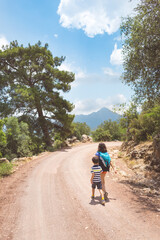 Obraz premium A woman with a backpack walks with her son on a mountain road.
