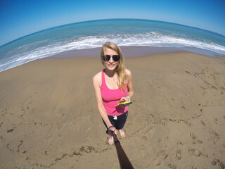The girl takes a selfie on the seashore. Beach photo.