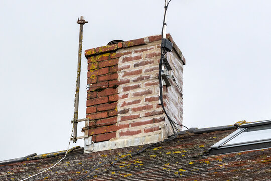 Chimney stack on a house roof, partly weather sealed and repaired with a recent repointing of its mortar cement stock photo image