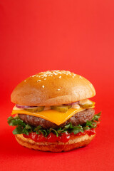 Delicious burger with beef and cheddar cheese on a red background. Tasty fresh unhealthy burgers with cheese and two patties. Fast food, unhealthy food concept.
