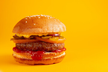 Delicious burger on a yellow background. Tasty fresh unhealthy burgers with cheese and two patties. Fast food, unhealthy food concept.