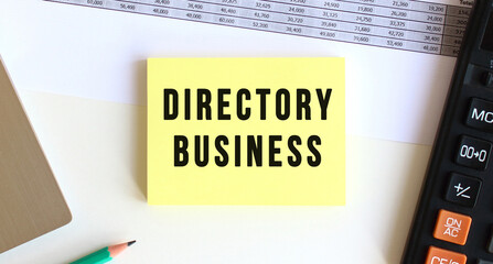Notepad with the text DIRECTORY BUSINESS on the desktop, near the laptop, calculator.