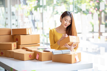 Naklejka premium Portrait of Starting small businesses SME owners female entrepreneurs working, box and check online orders to prepare to pack the boxes, sell to customers, sme business ideas online.