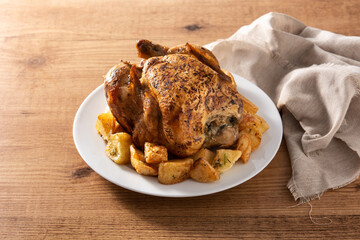 Homemade roasted chicken with potatoes on wooden table
