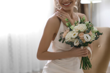 Young bride with beautiful wedding bouquet indoors, closeup