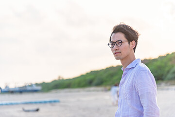 夕暮れのビーチで佇む男性