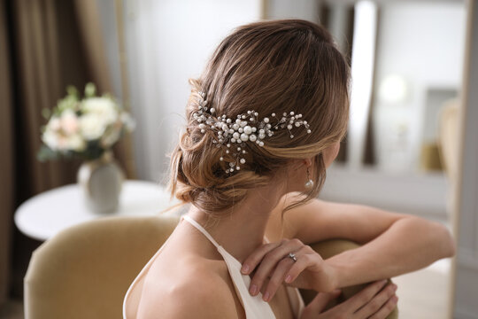 Young bride with elegant wedding hairstyle in room, back view