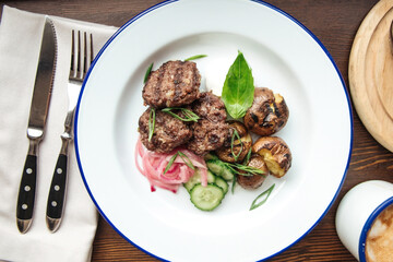 Mini beef cutlets with potato and cucumbers and a mug of coffee