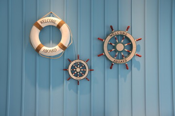  White life buoy on blue wooden wall, rudder boat helm with welcome message