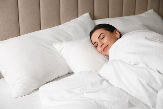 Young woman sleeping in bed covered with white blanket
