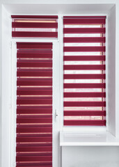 Fototapeta premium Red or magenta fabric roller blinds on the plastic window and balcony door. Window roller, duo system day and night. Modern shades on apartment window. Empty window sill and light walls. Vertical shot