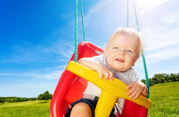 Fototapeta na wymiar Photo of the little boy on swings in park