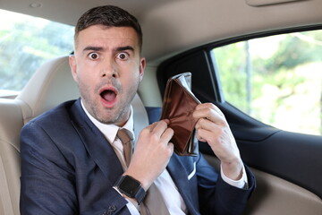 Puzzled businessman showing empty wallet in taxi