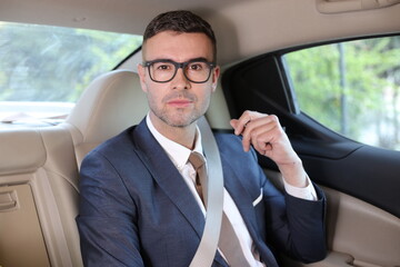 Businessman riding on luxurious car backseat