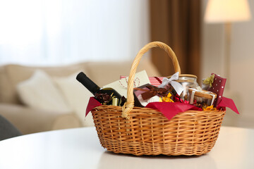 Wicker basket full of gifts on white table in living room