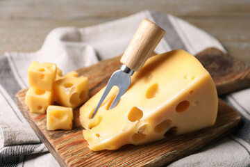 Tasty fresh cheese with fork on wooden board, closeup
