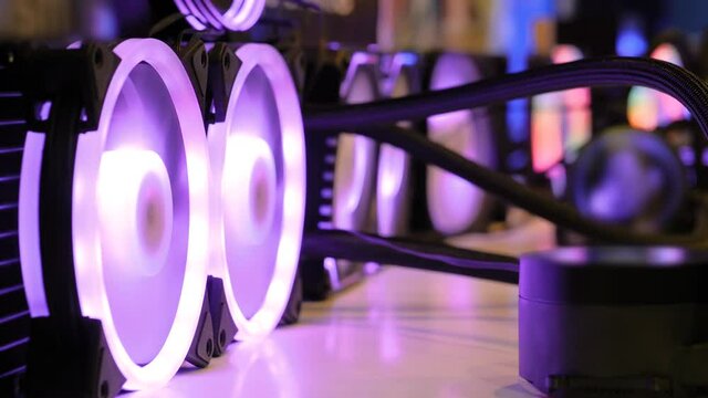 Many colorful pc coolers, cooling fans with neon LED light on table at computer exhibition, trade show - close up view. Technology, illumination, gaming, equipment, electronic concept