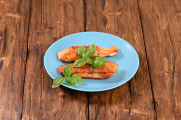 Fried red salmon with basil leaves.
