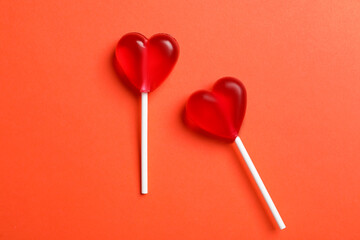 Sweet heart shaped lollipops on coral background, flat lay. Valentine's day celebration