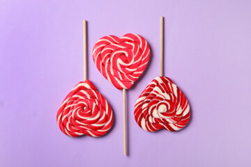 Sweet heart shaped lollipops on violet background, flat lay. Valentine's day celebration